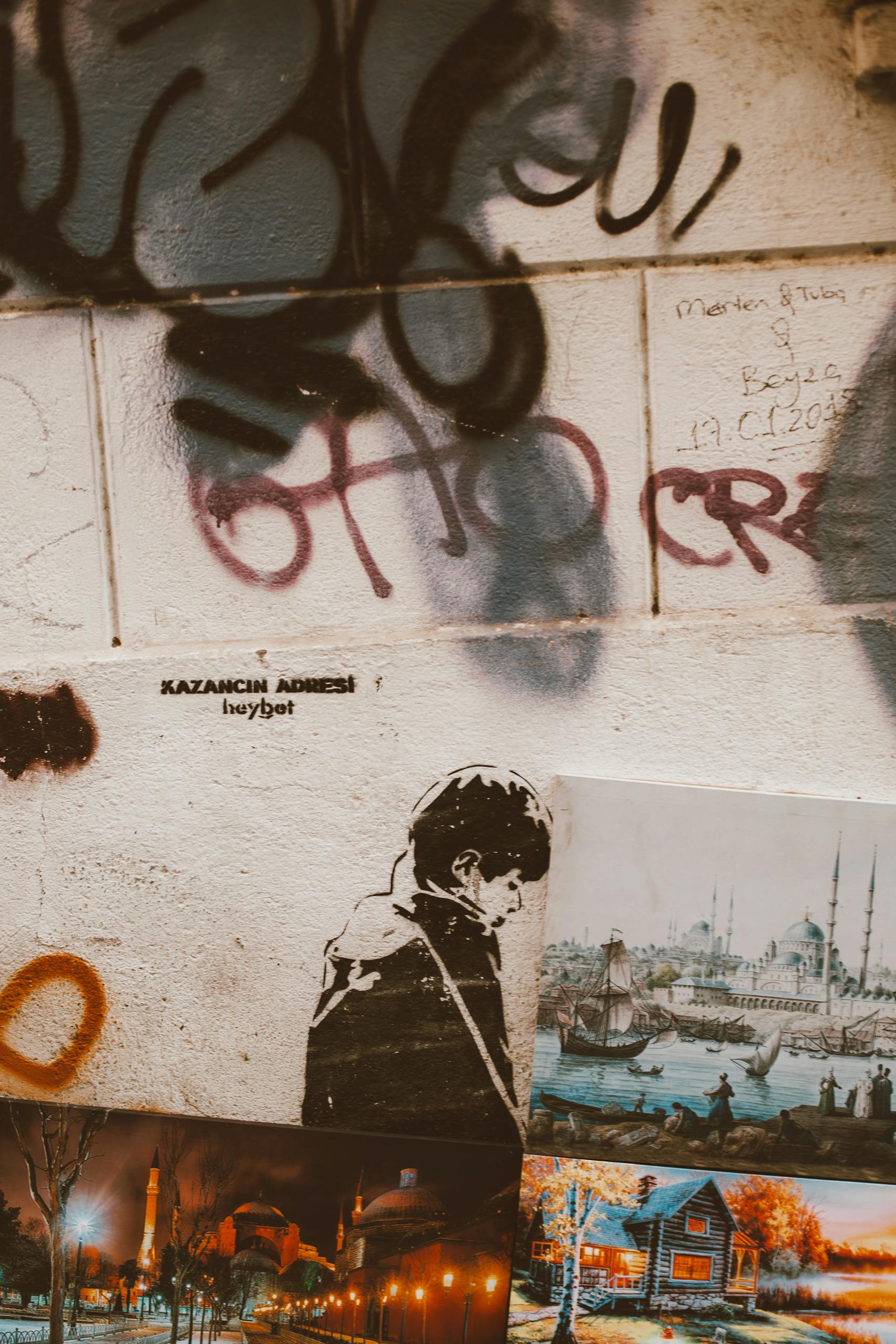 Graffiti and art posters on urban wall, showcasing street culture and creativity.